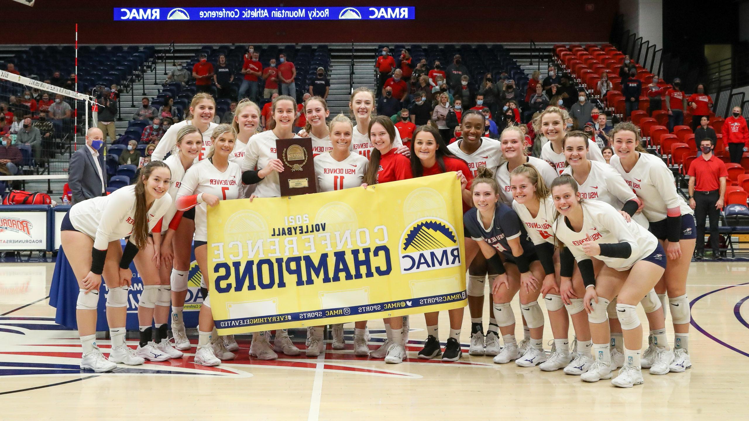 Roadrunners volleyball team celebrates the 2021 RMAC Championship with the banner.